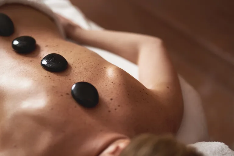 Hot-Stone-Massage mit warmen Basaltsteinen auf dem Rücken