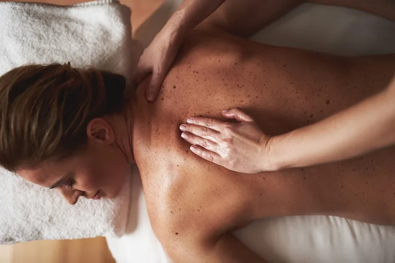 Rücken- und Nackenmassage mit Handflächendruck auf der Massageliege